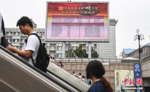 资料图：2017年8月23日，济南火车站广场大屏幕24小时循环播放失信被执行人信息，引得许多旅客驻足观看。 中新社记者 张勇 摄