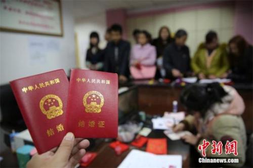资料图：在四川省内江市东兴区婚姻登记处，新人在展示刚领取的结婚证书。 兰自涛 摄